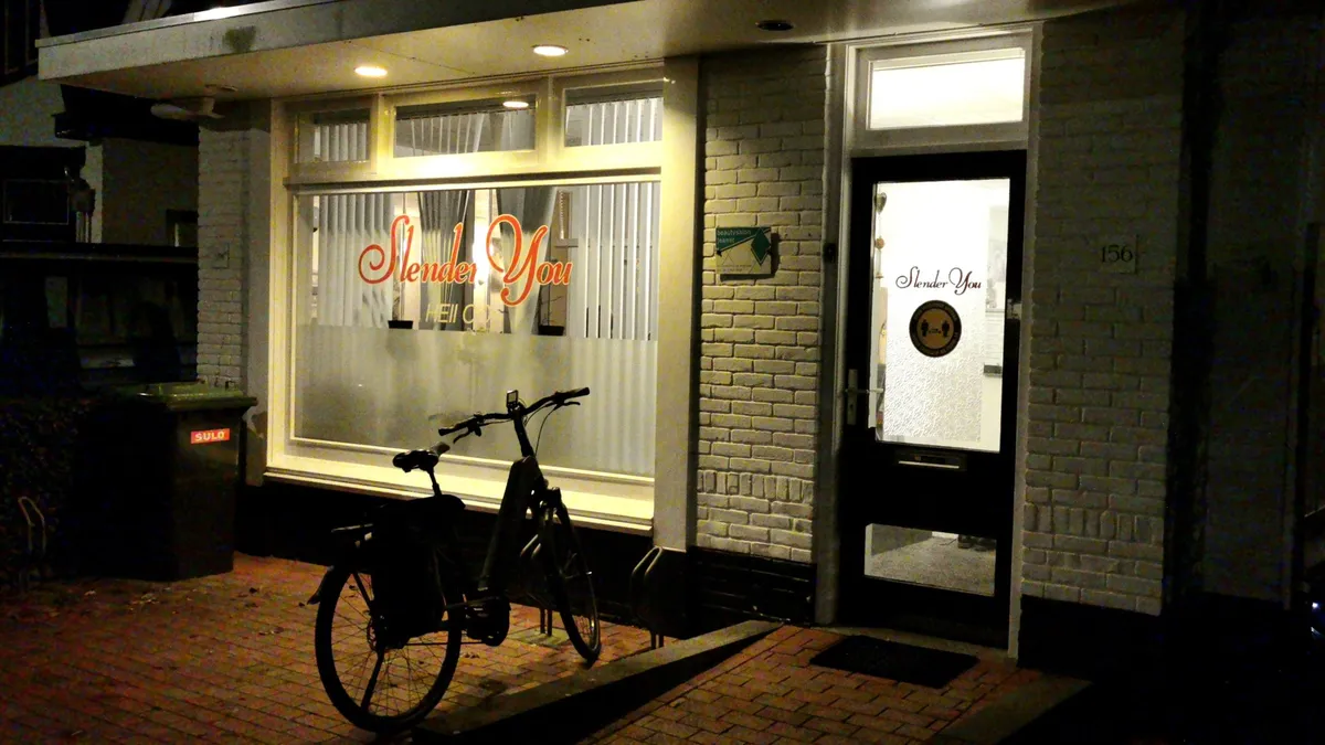 De verlichte gevel van Slender You Heiloo aan de Westerweg in de avond